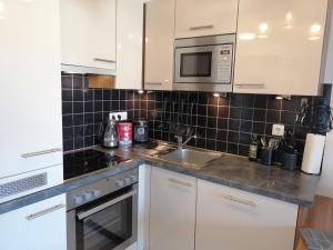 a kitchen with white cabinets and a sink and a microwave at Studio Steinbocks Chill in Kaprun