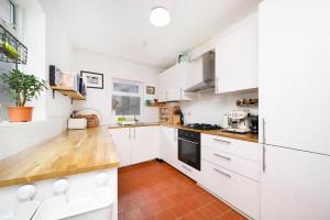 uma cozinha com armários brancos e piso em madeira em Charming 3BR Family-Friendly London Home em Londres