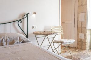 una camera con letto, tavolo e sedia di Masseria Torre Sant'Andrea (Antica Masseria Malapezza) a Melendugno