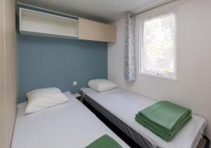 two beds in a small room with a window at Camping Le Both d'Orouet in Saint-Jean-de-Monts +99 photos