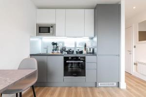 a kitchen with white cabinets and a stove top oven at Bright and Modern Studio Apartment in East Grinstead in East Grinstead
