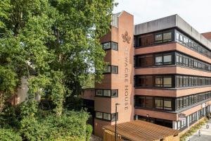 Bright and Modern Studio Apartment in East Grinstead في إيست غرينستيد: مبنى من الطوب الطويل عليه ساعة