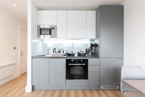 una cocina con armarios blancos y horno negro en Modern and Bright Studio in Central East Grinstead en East Grinstead