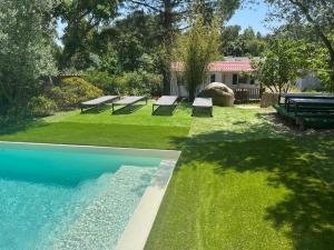ソエッタにあるLes Bergeries de Petralongaの芝生にベンチが置かれたプールのある裏庭