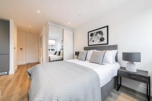 a bedroom with a large bed with a lamp on a table at Lovely Bright Studio Apartment in Central East Grinstead in East Grinstead