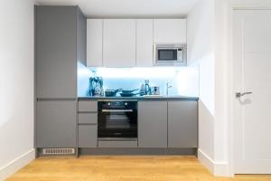 a kitchen with white cabinets and a black oven at Modern and Stylish Studio Apartment in East Grinstead in East Grinstead