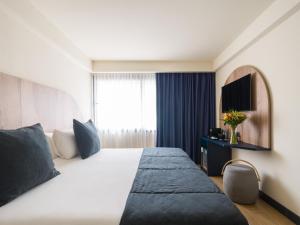 una camera d'albergo con un grande letto e una finestra di Sercotel Playa Canteras a Las Palmas de Gran Canaria