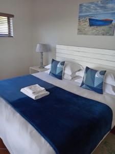 a large bed with blue and white sheets and pillows at Lêplek Guest House in Saldanha