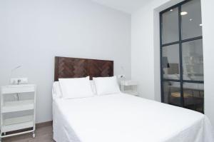 um quarto branco com uma cama grande e lençóis brancos em We Madrid Casa Duque em Madrid