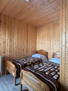 two beds in a room with wooden walls at Family Hostel Nika in Stepantsminda