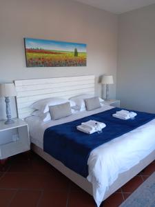 a bedroom with a large bed with two towels on it at Lêplek Guest House in Saldanha