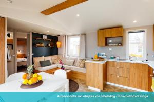 een keuken en een woonkamer met een bank en een tafel bij Siblu camping Lauwersoog in Lauwersoog