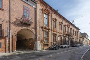 a brick building with cars parked on a street at San Gregorio Magno Apartment in Ferrara