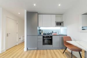 a kitchen with white cabinets and a table and chairs at Spacious and Bright Studio in East Grinstead in East Grinstead