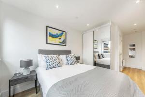 a white bedroom with a large white bed and a mirror at Spacious and Bright Studio in East Grinstead in East Grinstead