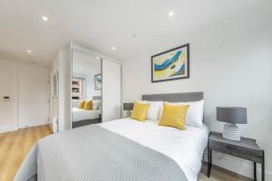 a white bedroom with a large bed with yellow pillows at Modern Studio in Central East Grinstead in East Grinstead