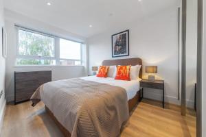 um quarto com uma cama com almofadas laranja e uma janela em Modern and Bright 1 Bed Apartment in East Grinstead em East Grinstead