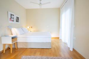 um quarto branco com uma cama e uma mesa em boo premium living ioannina em Anatolí