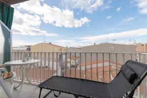 a balcony with a black chair and a table on a roof at Quimanna Calafell Beach in Calafell