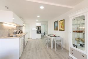 a white kitchen with a table and chairs in it at Quimanna Calafell Beach in Calafell