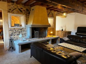 a living room with a fireplace and leather furniture at Les Janets 12 personnes in Saint-Sauveur-en-Puisaye
