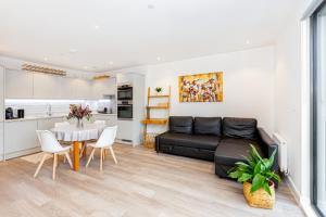 a living room with a black couch and a table at Sensational 2BR wViews & Balcony in Wandsworth in London