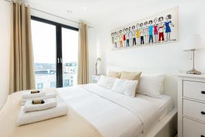 a bedroom with a large white bed with a window at Sensational 2BR wViews & Balcony in Wandsworth in London