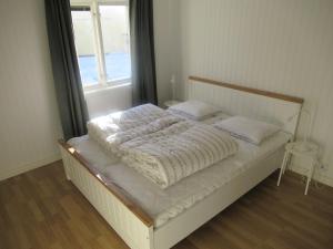 a bed with a white comforter and a window at Villa Indalsälven in Hammarstrand