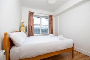 Un dormitorio con una cama grande y una ventana en Flat w/ Balcony & Canal view - 4min to station, en Dublín