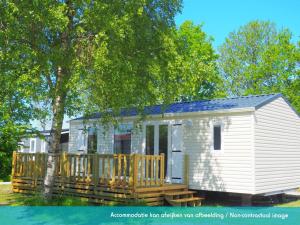 uma pequena casa branca com um deque de madeira em Siblu camping Lauwersoog em Lauwersoog