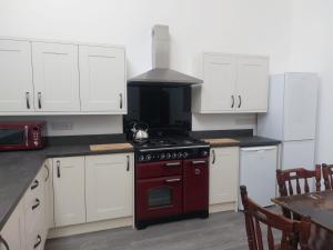 a kitchen with white cabinets and a stove top oven at Cwm Clyd - Carthouse in Rhayader