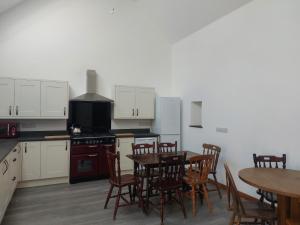 a kitchen with a table and chairs and a kitchen with white cabinets at Cwm Clyd - Carthouse in Rhayader