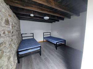 two beds in a room with a stone wall at Cwm Clyd - Carthouse in Rhayader
