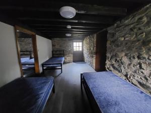 a room with two beds and a stone wall at Cwm Clyd Longhouse in Llanwrthwl
