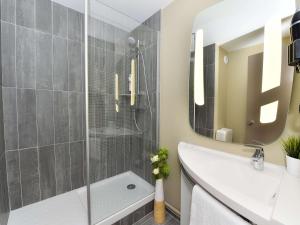 een badkamer met een douche en een witte wastafel bij ibis Beaune La Ferme Aux Vins in Beaune