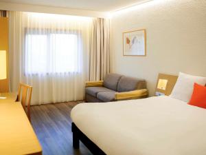 a hotel room with a bed and a couch at Novotel Porto Gaia in Vila Nova de Gaia