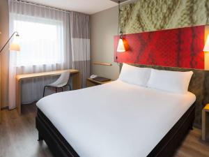 una camera d'albergo con un grande letto bianco e una finestra di Ibis Irun a Irún