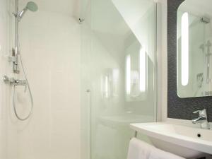 a white bathroom with a shower and a sink at ibis Granville Port De Plaisance in Granville