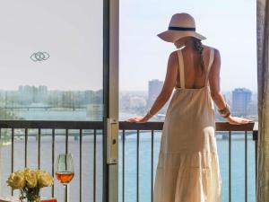 a woman in a white dress and hat standing on a balcony at Sofitel Cairo Nile El Gezirah in Cairo
