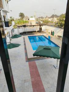 einen Blick über einen Pool mit Sonnenschirm in der Unterkunft Valentino Swiss Hotel and Apartment in Port Harcourt