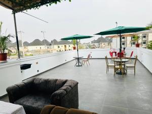 un patio con sillas, mesas y sombrillas en la azotea en Valentino Swiss Hotel and Apartment, en Port Harcourt