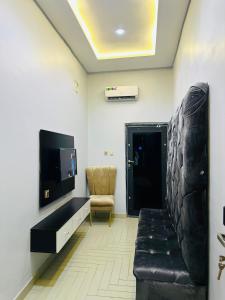 sala de estar con sofá, TV y silla en Valentino Swiss Hotel and Apartment, en Port Harcourt