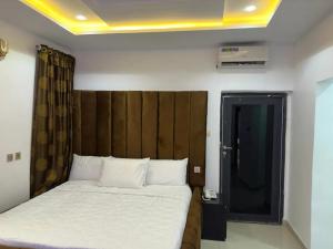 1 dormitorio con 1 cama con cabecero de madera en Valentino Swiss Hotel and Apartment, en Port Harcourt