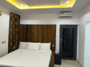 a bedroom with a bed with a wooden headboard at Valentino Swiss Hotel and Apartment in Port Harcourt