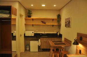 uma pequena cozinha com um lavatório e uma mesa em Suite Negri em Canela
