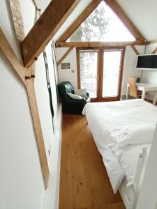 a bedroom with a bed and a chair in a room at LITTLE OAK - Kingsize Double Oak Studio - Sleeps 2 - Quirky - Rural in Haslemere
