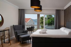 a bedroom with a bed and a chair and a window at Villa Suartini Viganj Pool or Jakuzzi in Viganj +22 photos