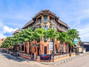 a large building with palm trees in front of it at Mercure Samui Chaweng Tana in Chaweng