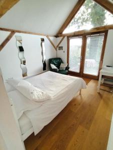 a bedroom with a white bed in a room with windows at LITTLE OAK - Kingsize Double Oak Studio - Sleeps 2 - Quirky - Rural in Haslemere