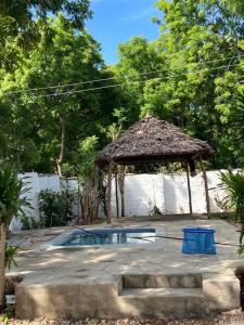 een klein zwembad in een tuin met een strohut bij TabaSamu Terrace in Mombasa